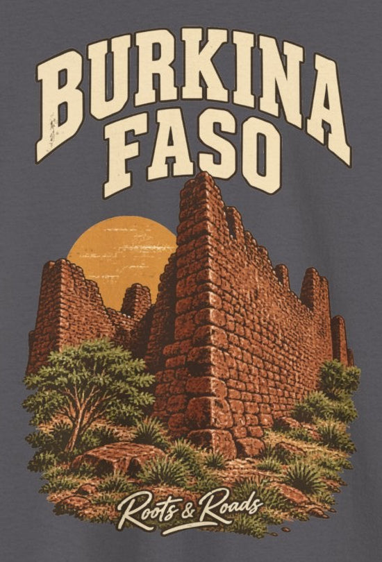 Print detail on Charcoal cotton showing BURKINA FASO lettering above Loropéni-inspired stone walls, plants and an ochre sun, with Roots & Roads script.