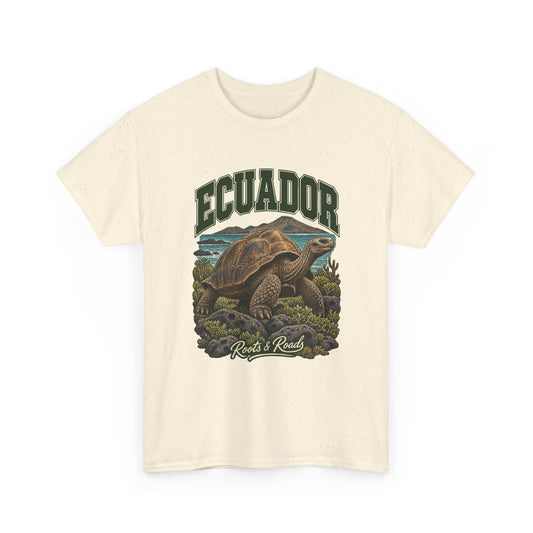 Front view of a Natural Gildan 5000 T-shirt with green ECUADOR lettering above a giant tortoise, volcanic rocks, low plants and coastal water, finished with Roots & Roads script.