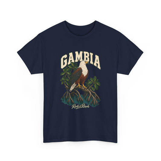 Front view of a Navy Gildan 5000 T-shirt with cream GAMBIA lettering above a white-headed fish eagle, mangrove roots and still water, finished with Roots & Roads script.