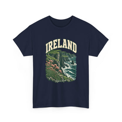 Front view of a Navy Gildan 5000 T-shirt with cream IRELAND lettering, green sea cliffs, Atlantic waves and pink coastal flowers, and Roots & Roads script.