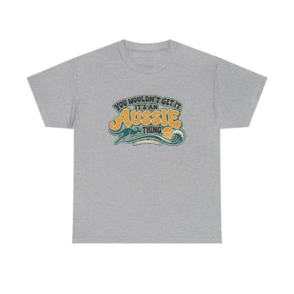 Front view of the Sport Grey Aussie Thing T-shirt with “You wouldn’t get it. It’s an Aussie thing.” gold bubble lettering, cream contours, a kangaroo, curling wave and sunset.