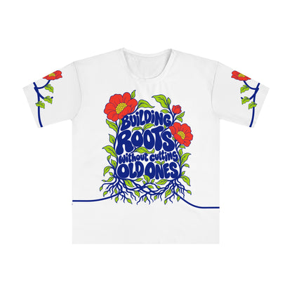 Front of the Roots & Roads “Building roots without cutting old ones” T-shirt with cobalt lettering, coral flowers, lime leaves and two connected root systems on white.
