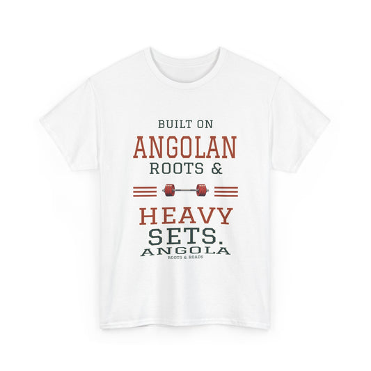White Angola gym T-shirt, front view. “Built on Angolan roots & heavy sets.” Varsity lettering and barbell artwork with Angola and Roots & Roads below.