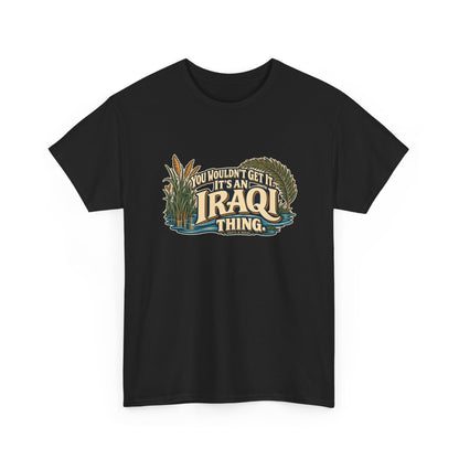 Black Iraq Iraqi Thing T-shirt, shaped front view with oversized cream lettering, marsh reeds, palm fronds and flowing blue water; “You wouldn’t get it. It’s an Iraqi thing.”