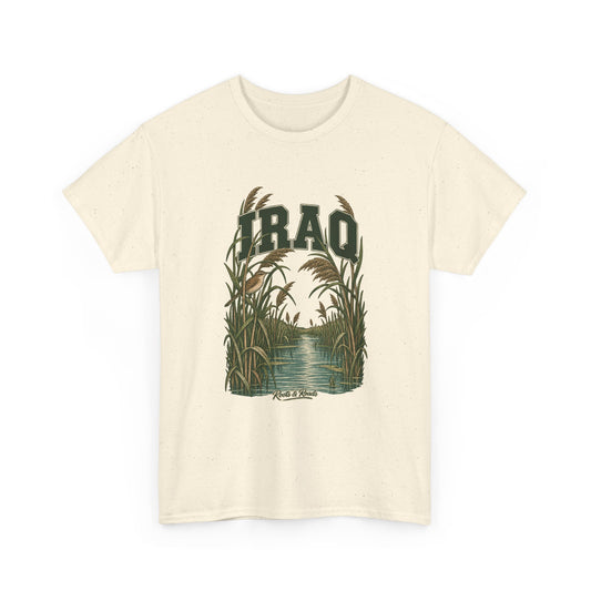 Front view of a Natural Gildan 5000 T-shirt with deep-green IRAQ lettering, a small bird, tall reeds and a quiet marsh channel, and Roots & Roads script.