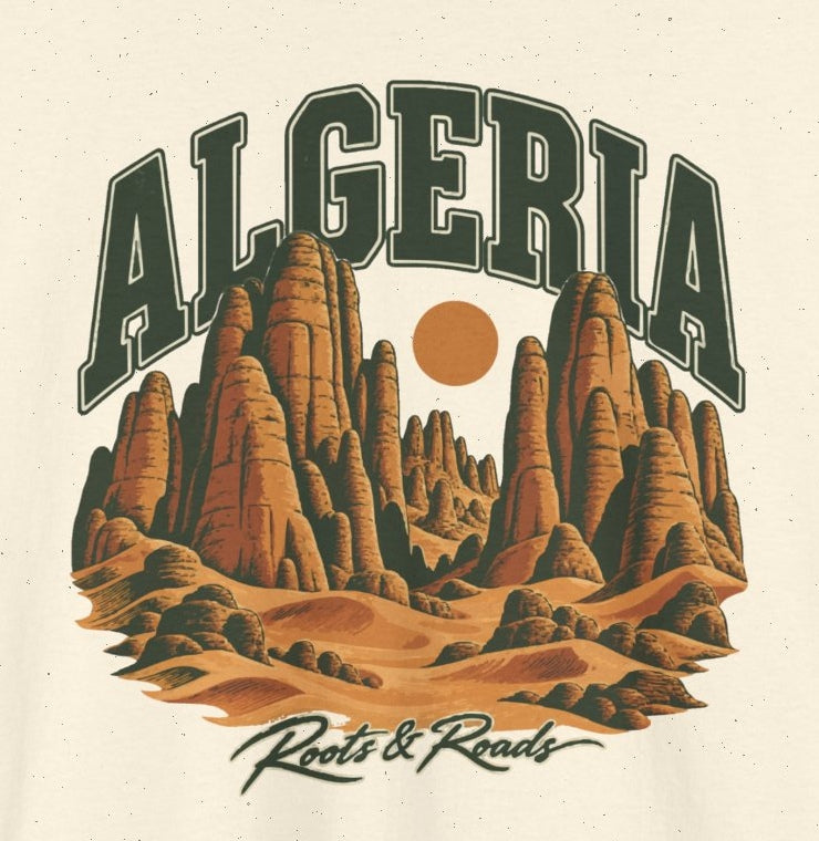Print detail of Algeria Fresh Prints artwork on Natural cotton: forest-green arched ALGERIA lettering, ochre sandstone towers and dunes, a round sun, and Roots & Roads script.