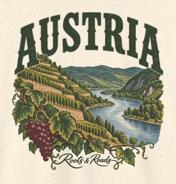 Print detail on Natural cotton showing green AUSTRIA lettering, riverside vineyard terraces, grape leaves and burgundy grapes, with Roots & Roads script.