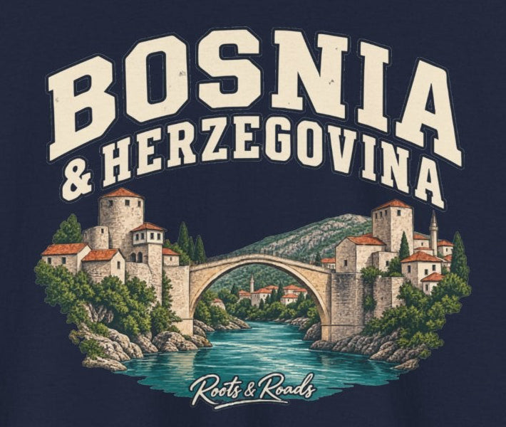 Print detail on Navy cotton showing BOSNIA & HERZEGOVINA lettering above a Mostar-inspired stone bridge, red roofs and teal river, with Roots & Roads script.