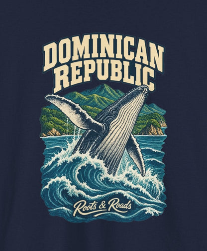 Print detail cropped from the Navy Dominican Republic supplier T-shirt mockup, showing cream two-line DOMINICAN REPUBLIC lettering, a breaching whale, blue waves and green coastal mountains and Roots & Roads script.
