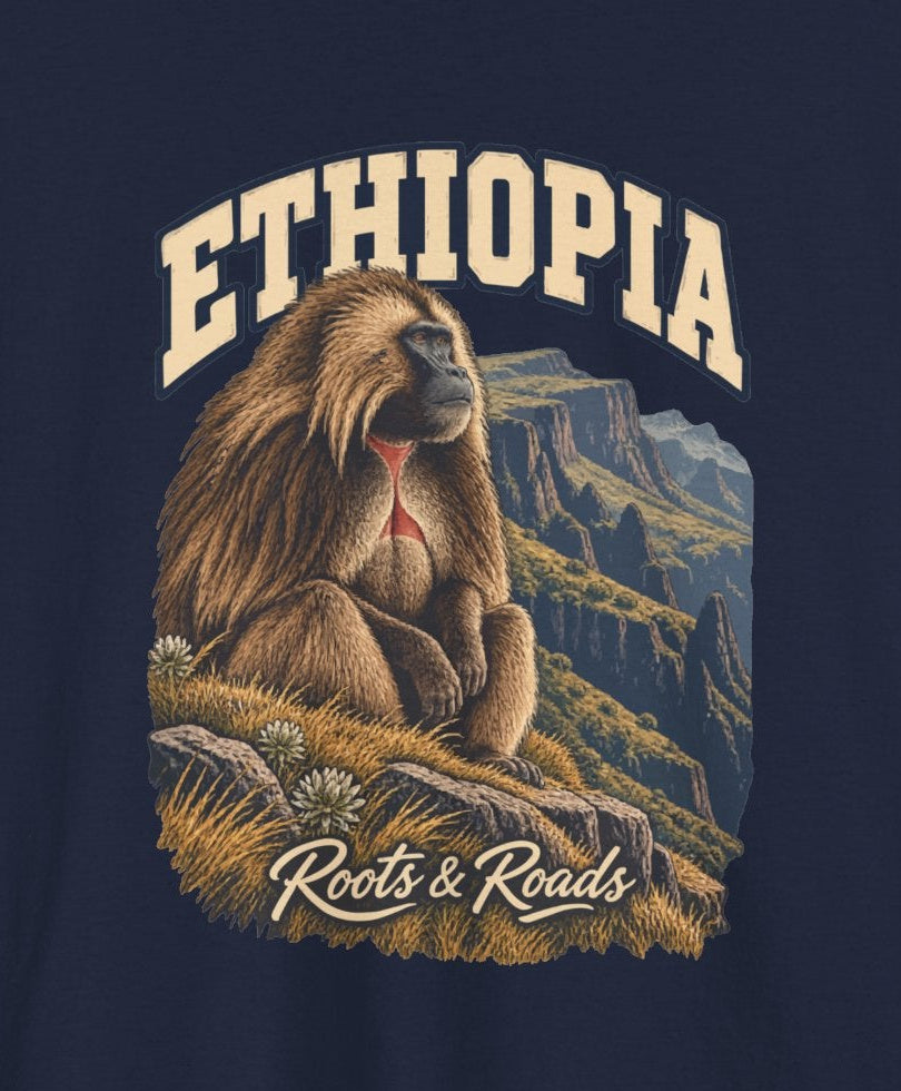 Print detail cropped from the Navy Ethiopia supplier T-shirt mockup, showing cream ETHIOPIA lettering, a shaggy gelada, grasses and steep mountain escarpments and Roots & Roads script.