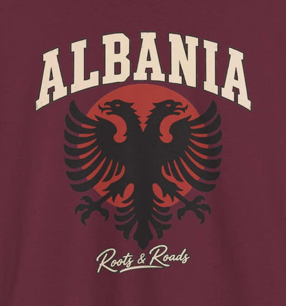 Close-up of the Albania Fresh Prints front design on Maroon cotton: cream arched lettering, a black double-headed eagle, muted red circle and Roots & Roads script. Cropped from the supplier mockup.